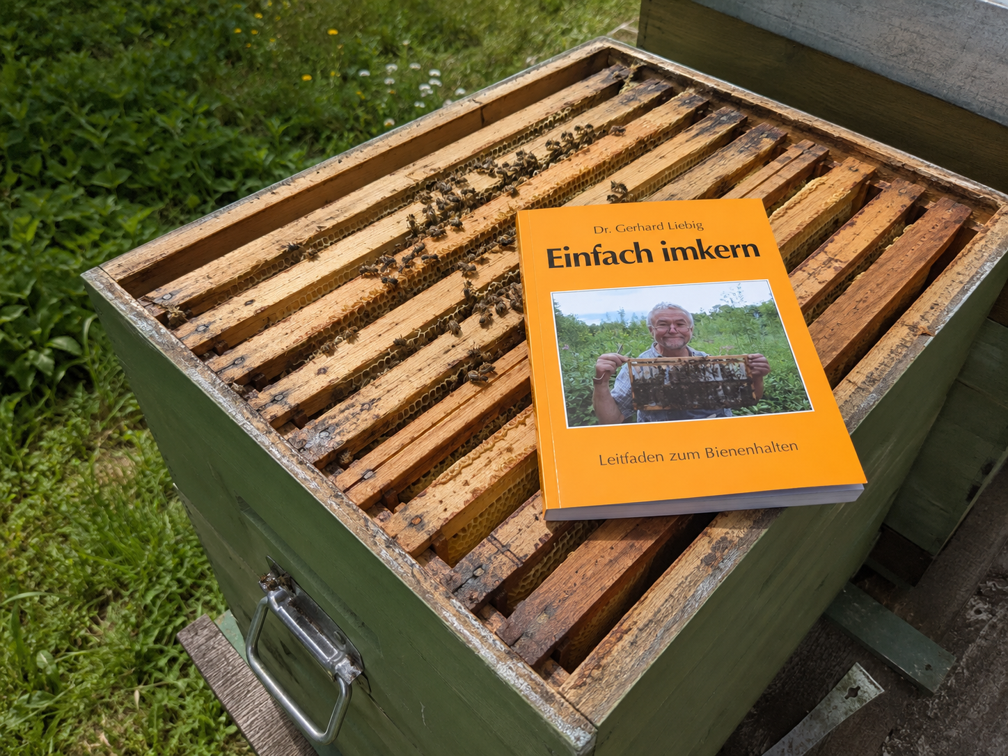 Eine Bienenbeute steht offen auf einer Palette. Darauf liegt das Buch "Einfach imkern" von Dr. Gerhard Liebig